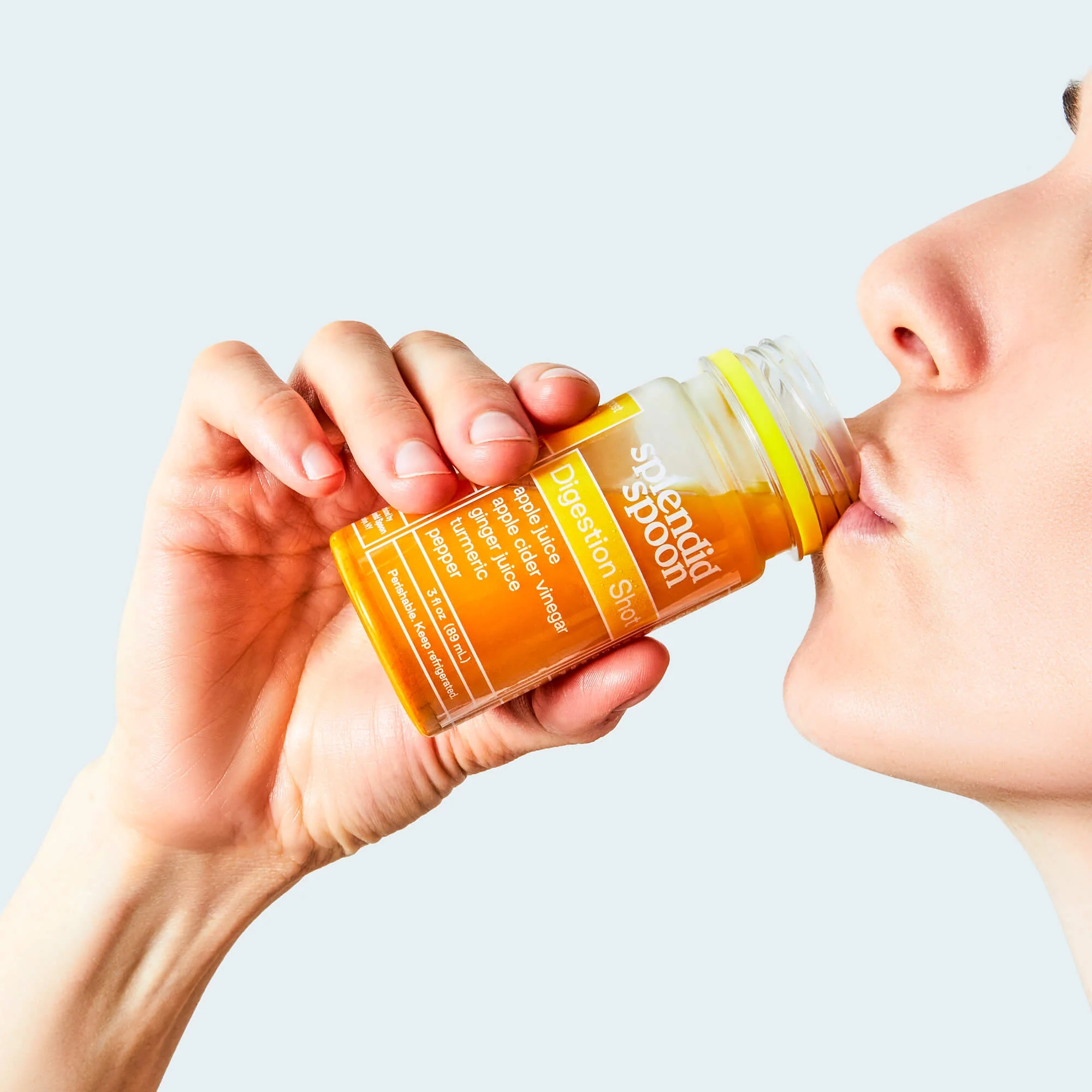 Person drinking a Splendid Spoon shot from a small bottle
