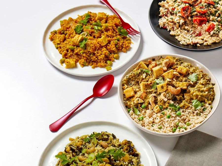 Three plates of prepared dishes with a red spoon